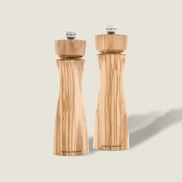 #salt&pepperset Two Portobello Olive Wood Salt & Pepper Mills by Cole & Mason, each with a precision grinding mechanism and natural grain pattern, stand side by side on a light background. Both are branded “Cole & Mason” at the base.