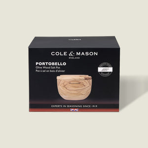 A Cole & Mason box displays the Portobello Olive Wood Salt Cellar—a small, round wooden container with a lid. The mostly black packaging features white text and a product image, making it perfect for stylish kitchen decor.