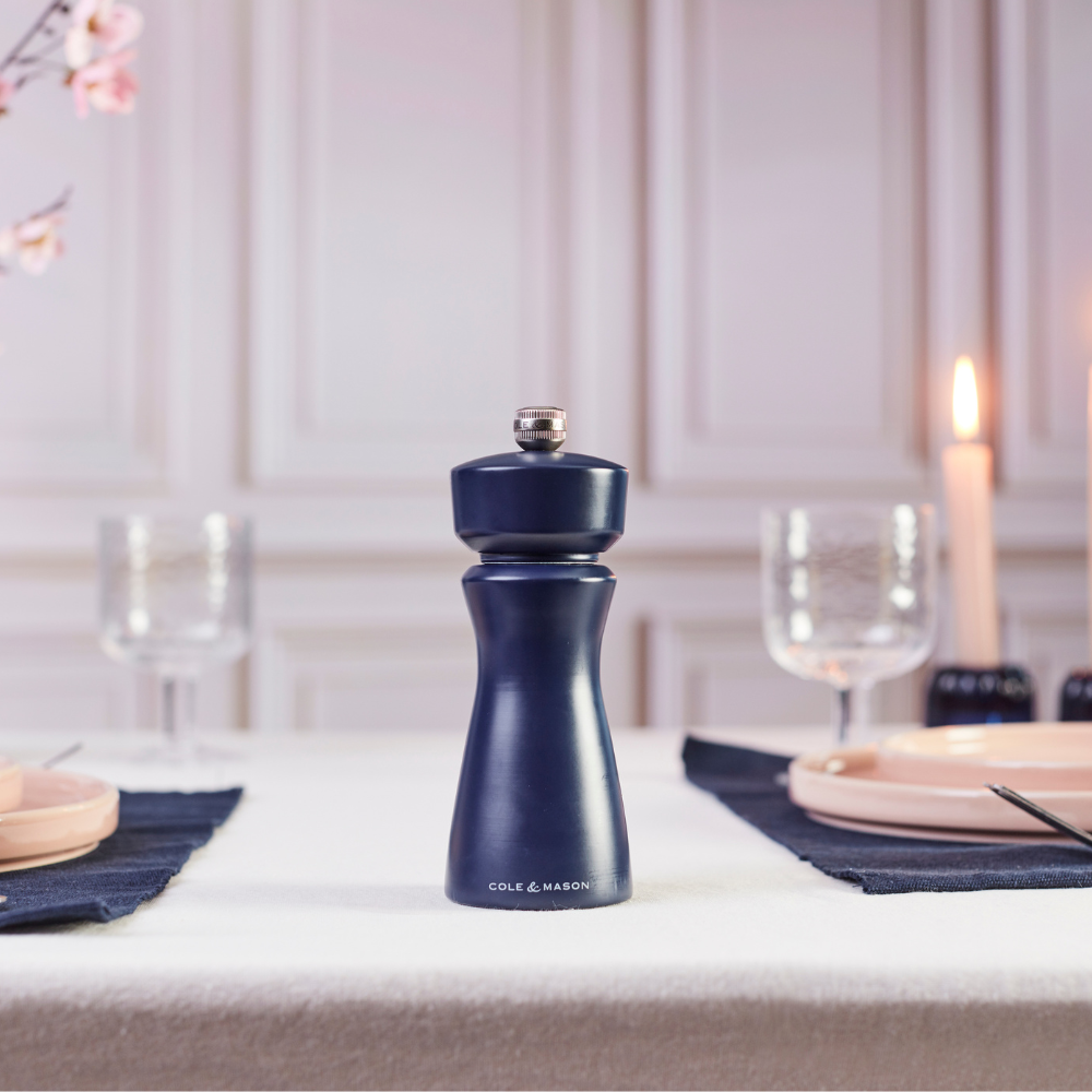 A Persian Blue Cole & Mason Kenton Salt & Pepper Mill, featuring a high-quality ceramic grinder and a sleek design, stands upright on a light beige background, casting a soft shadow to the right.