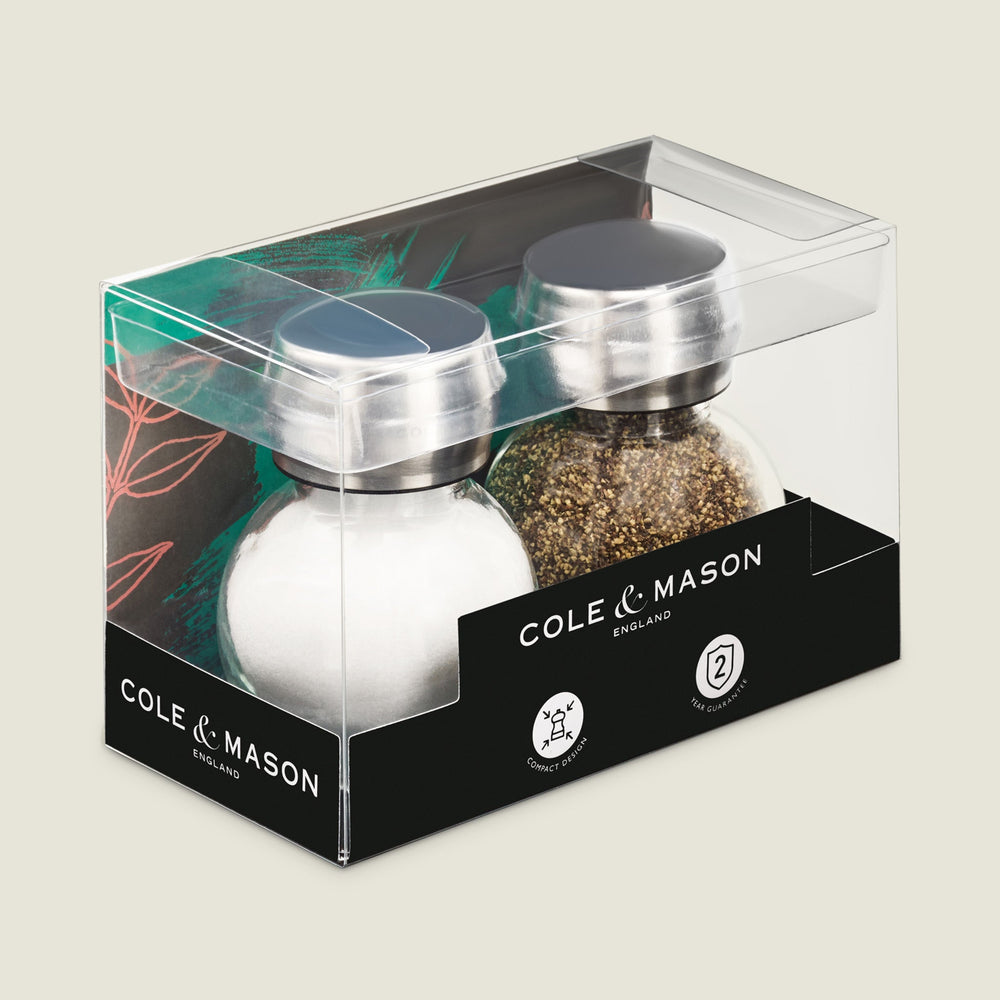 The Cole & Mason Darlington Shakers Set includes two glass jars with stainless steel lids—one empty, one filled with cracked black pepper. Both feature a sleek design and Cole & Mason branding, perfect for stylish seasoning.