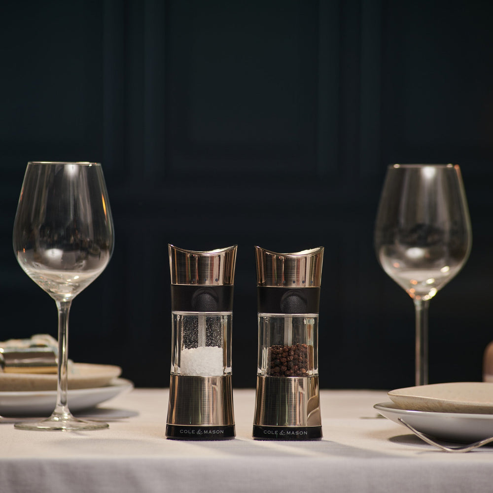 #salt&pepperset
Two Cole & Mason Horsham Salt & Pepper Mills are shown side by side; the left holds coarse salt, the right, whole peppercorns. Both have clear midsections to display contents and offer high-performance grinding with adjustable settings.