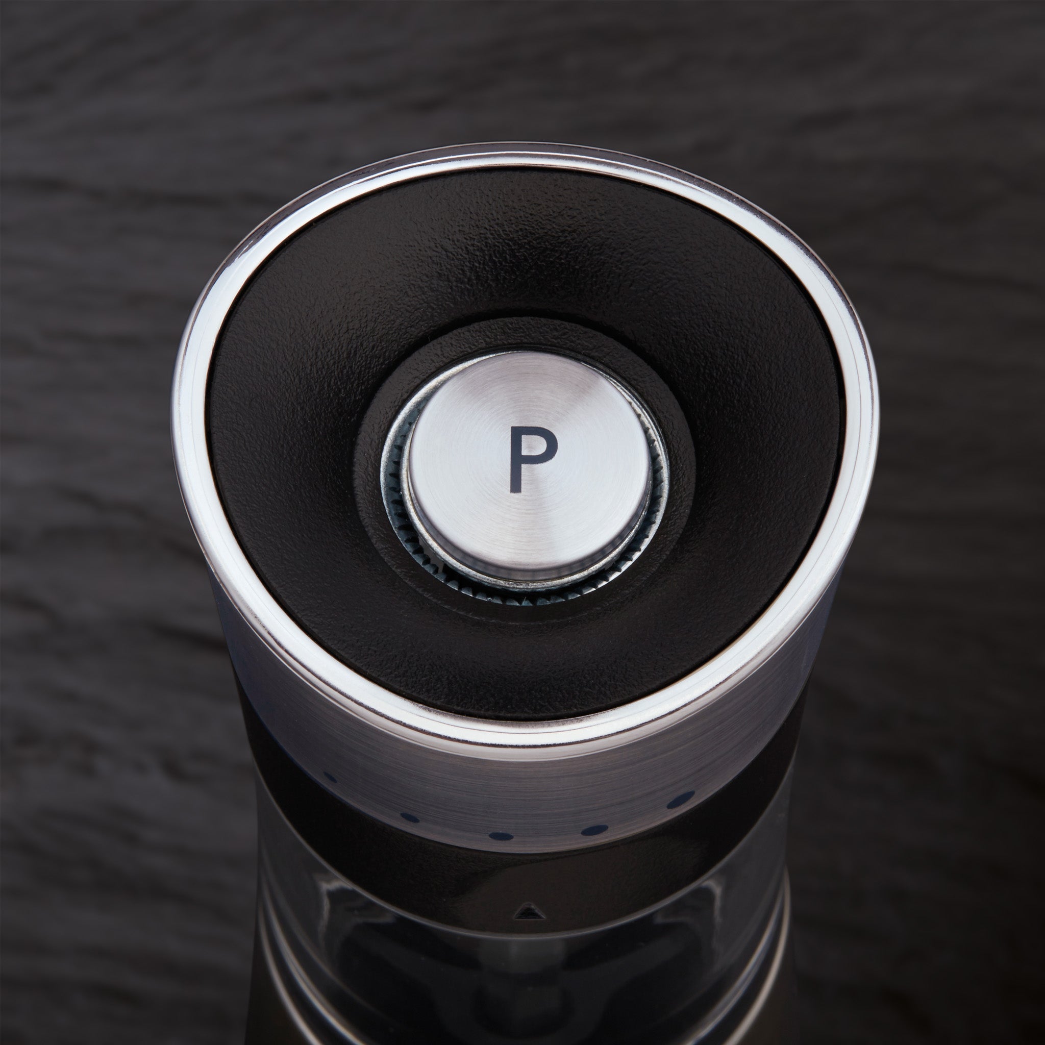 Close-up of a modern car gear selector with a metallic button labeled P for park, set against a dark background.